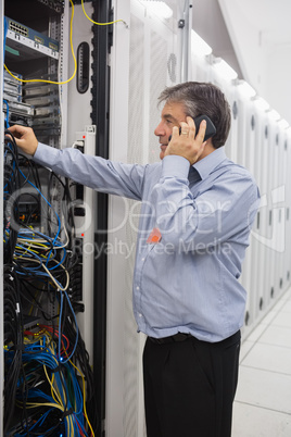 Male technician phoning while repairing a server