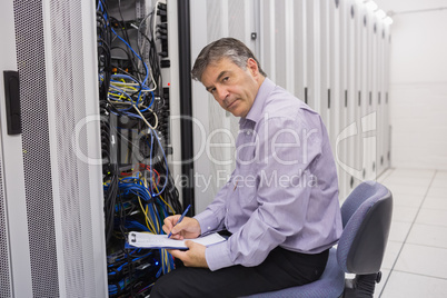Technician looking up from making notes on server