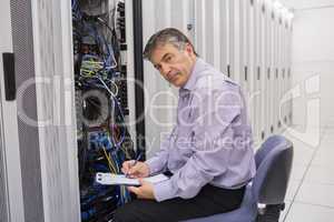 Technician looking up from making notes on server