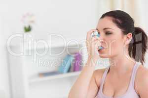 Woman using asthma inhaler in living room