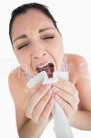 Woman sneezing into a tissue