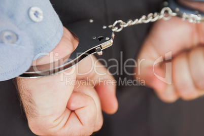 Hands with handcuffs clenching fists