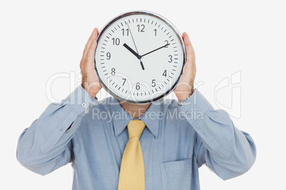 Businessman holding clock in front of face