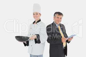 Businessman holding digital tablet and female chef with frying p