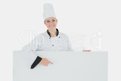 Happy female chef pointing at billboard