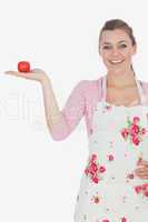 Young woman wearing apron while holding tomato