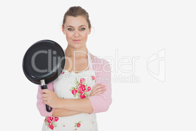 Portrait of woman in apron holding frying pan