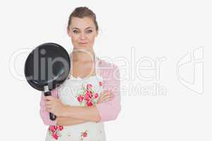 Portrait of woman in apron holding frying pan