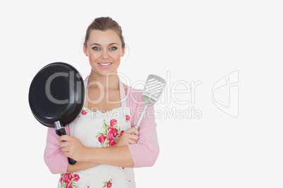 Young woman holding frying pan and spatula