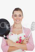 Confident woman holding frying pan and spatula