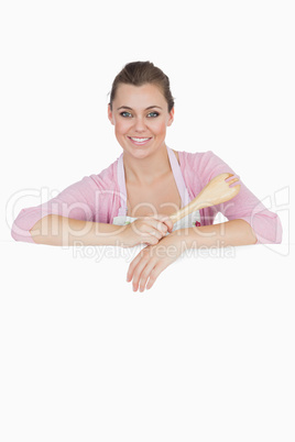 Maid holding spoon as she leans on blank billboard