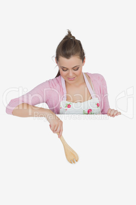 Maid pointing with wooden spoon on billboard
