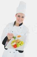 Female chef seasoning meal with parsley