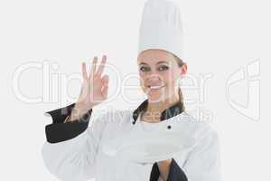 Chef holding an empty plate as she shows ok sign