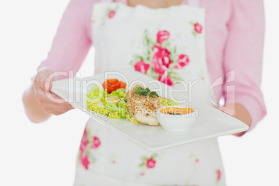 Woman in apron holding plate of healthy meal