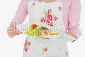 Woman in apron holding plate of healthy meal