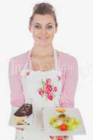 Beautiful maid holding plates of pastry and healthy food
