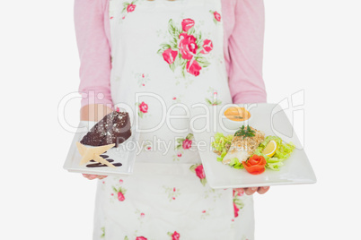 Maid in apron holding plates of pastry and meal