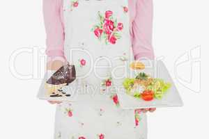 Maid in apron holding plates of pastry and meal