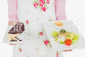 Maid holding plates of healthy meal and pastry