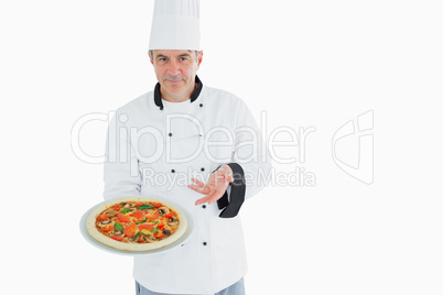 Confident chef displaying pizza