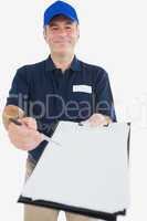 Happy delivery man holding out clipboard for signature