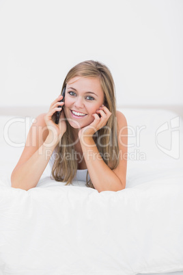 Joyful woman phoning lying on the bed