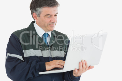 Repairman in coveralls using laptop