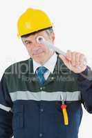 Mature repairman looking through wrench