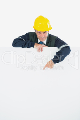 Mature repairman pointing at blank billboard