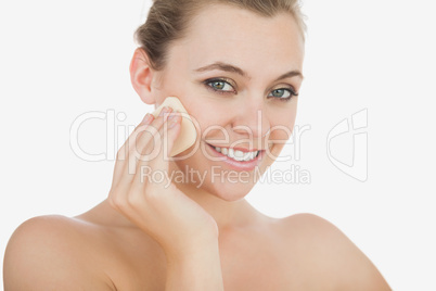 Young woman using powder puff