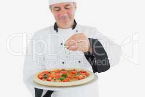 Chef garnishing pizza with coriander leaves