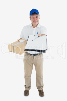 Happy courier man with package holding out clipboard