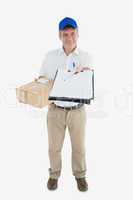 Happy courier man with package holding out clipboard