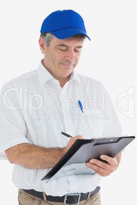 Mature delivery man writing on clipboard