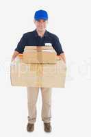 Mature courier man carrying stack of cardboard boxes