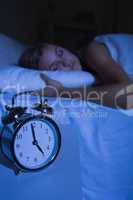 Alarm clock in front of a sleeping woman