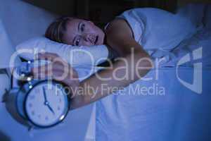 Awakening woman stopping her alarm clock