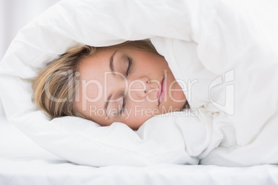 Sleeping woman hiding under the duvet