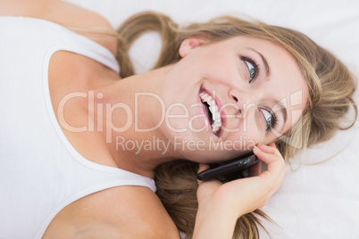 Happy woman phoning lying on the bed