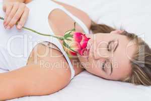 Blonde woman lying on the bed with a rose