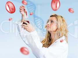 Woman in lapcoat looking at red chemical liquid