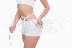 Midsection of woman measuring waist