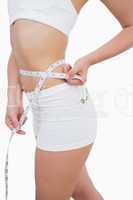 Midsection of fit woman measuring waist