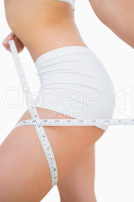 Woman measuring thigh with measuring tape