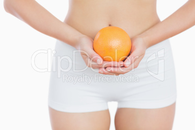 Fit woman holding fresh orange