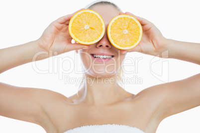 Woman holding slices of orange in front of eyes