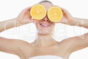 Woman holding slices of orange in front of eyes