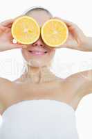 Happy woman covering eyes with slices of orange
