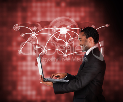 Smiling businessman holding laptop against a background